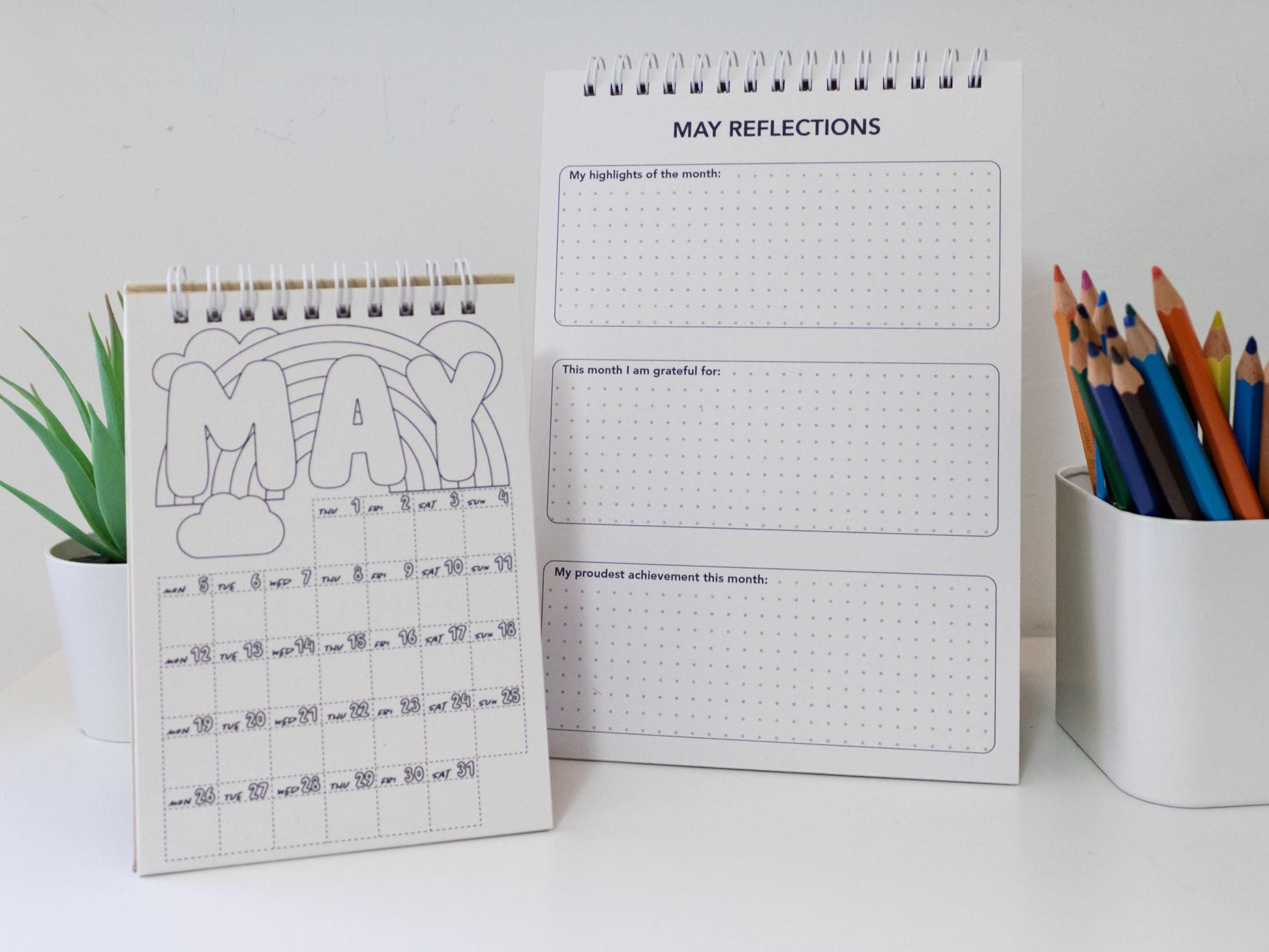 Two 2026 colouring desk calendar on a white surface with coloured pencils - May page front and back