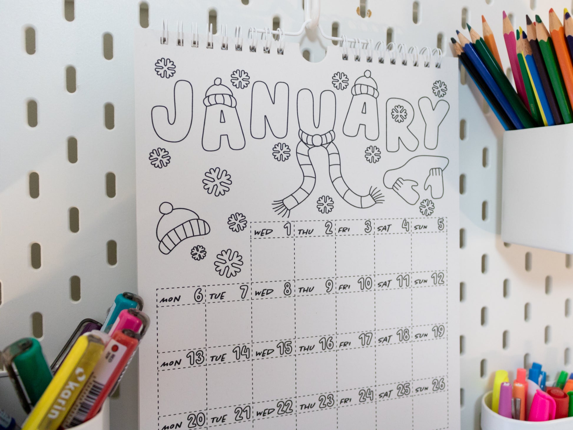 2026 Colouring Calendar on a pegboard with markers and crayons - January page