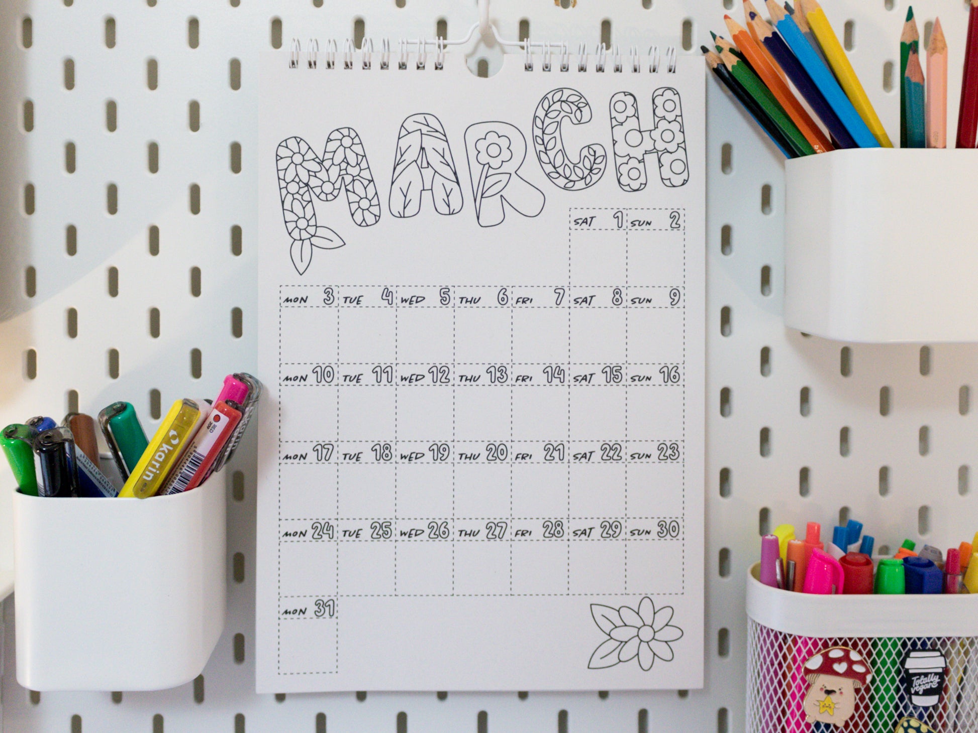 2026 Colouring Calendar on a pegboard with markers and crayons - March page