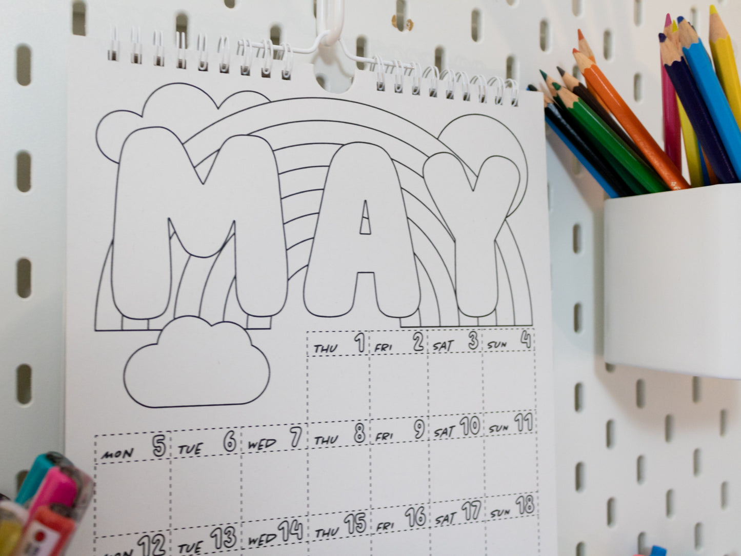 2026 Colouring Calendar on a pegboard with markers and crayons - May page