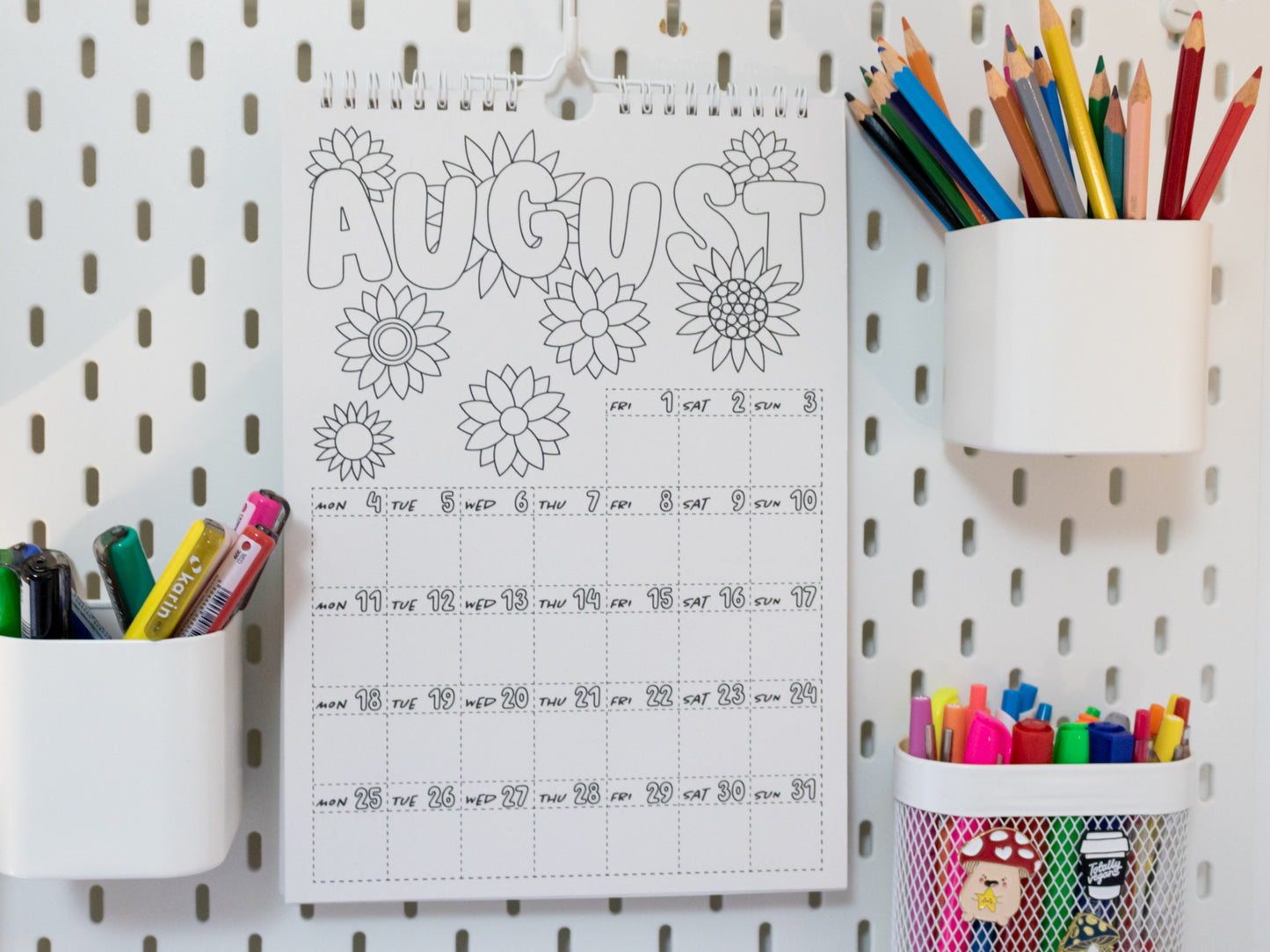 2026 Colouring Calendar on a pegboard with markers and crayons - August page
