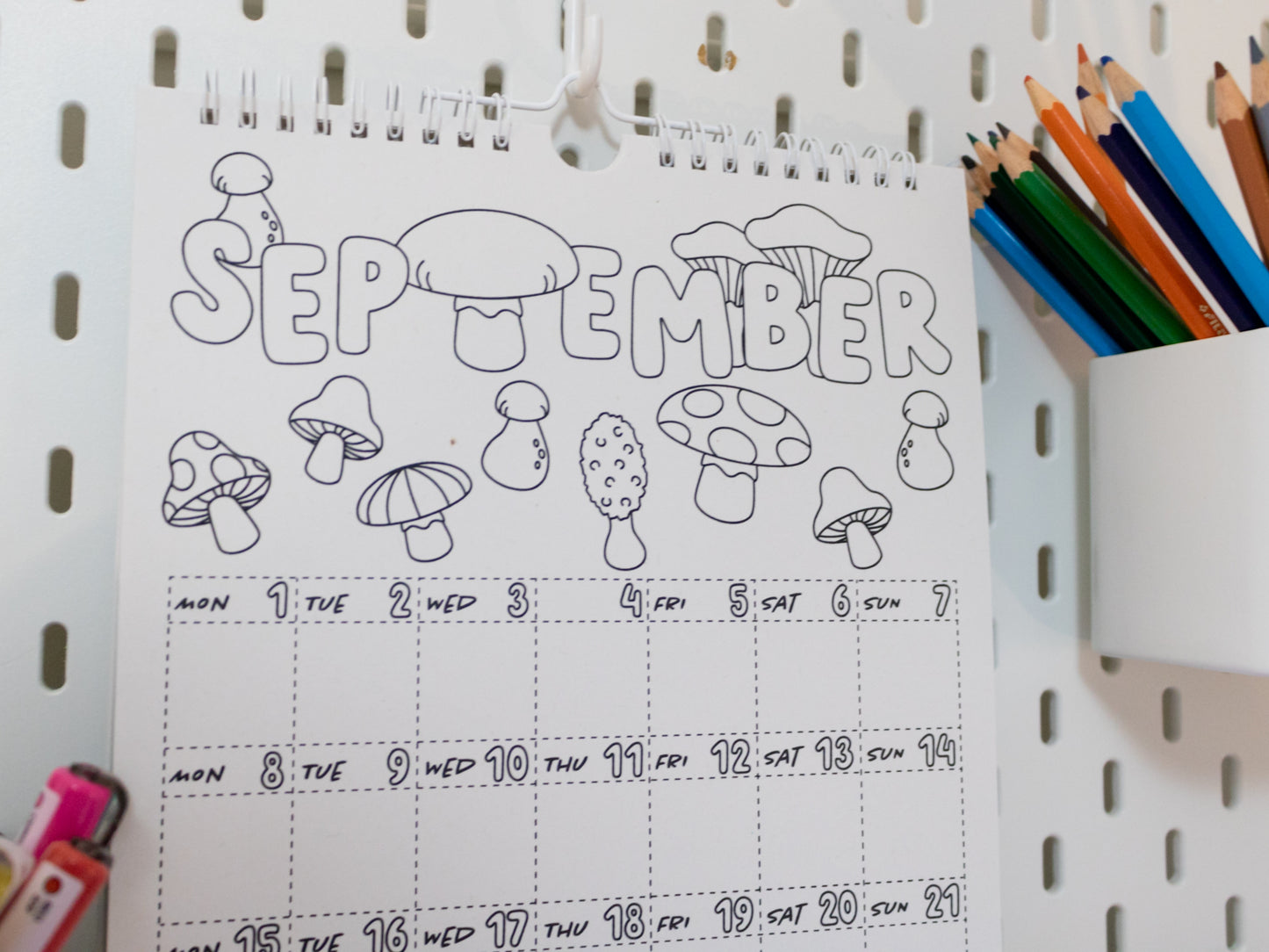2026 Colouring Calendar on a pegboard with markers and crayons - September page