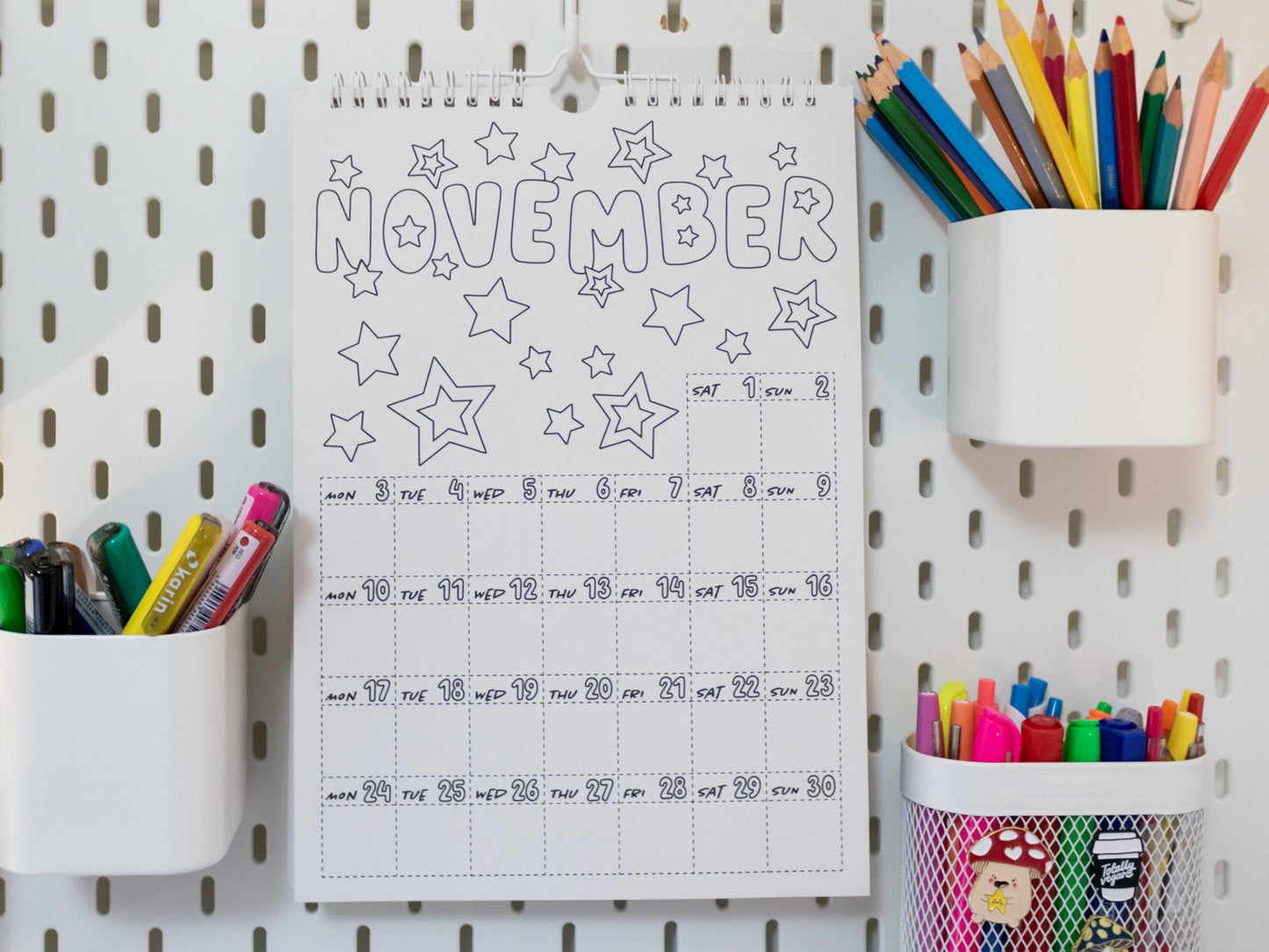 2026 Colouring Calendar on a pegboard with markers and crayons - November page