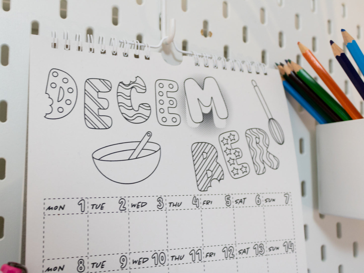 2026 Colouring Calendar on a pegboard with markers and crayons - December page