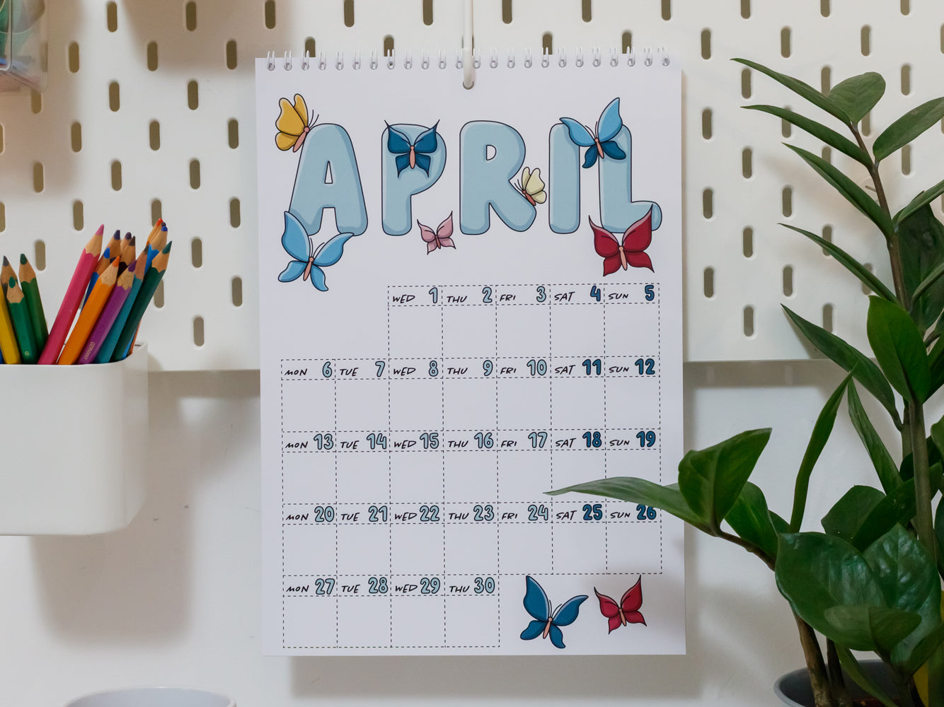 2026 Wall Calendar: April page with butterfly designs on a white pegboard background