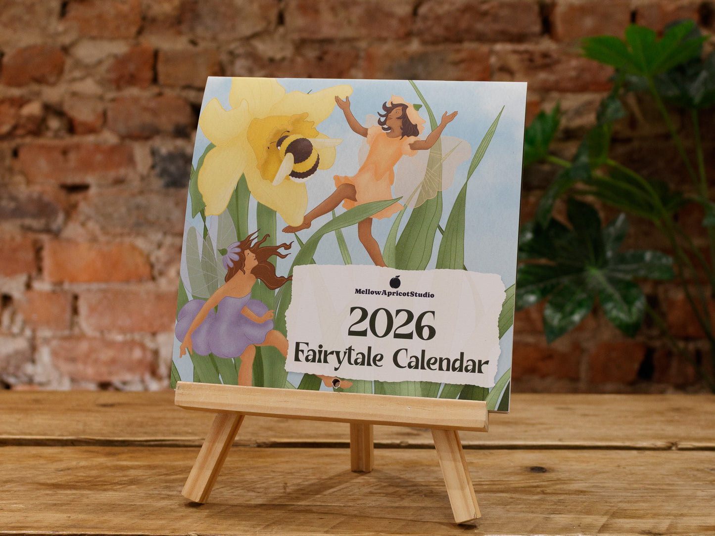 2026 Fairytale Calendar on a wooden stand with a brick wall background