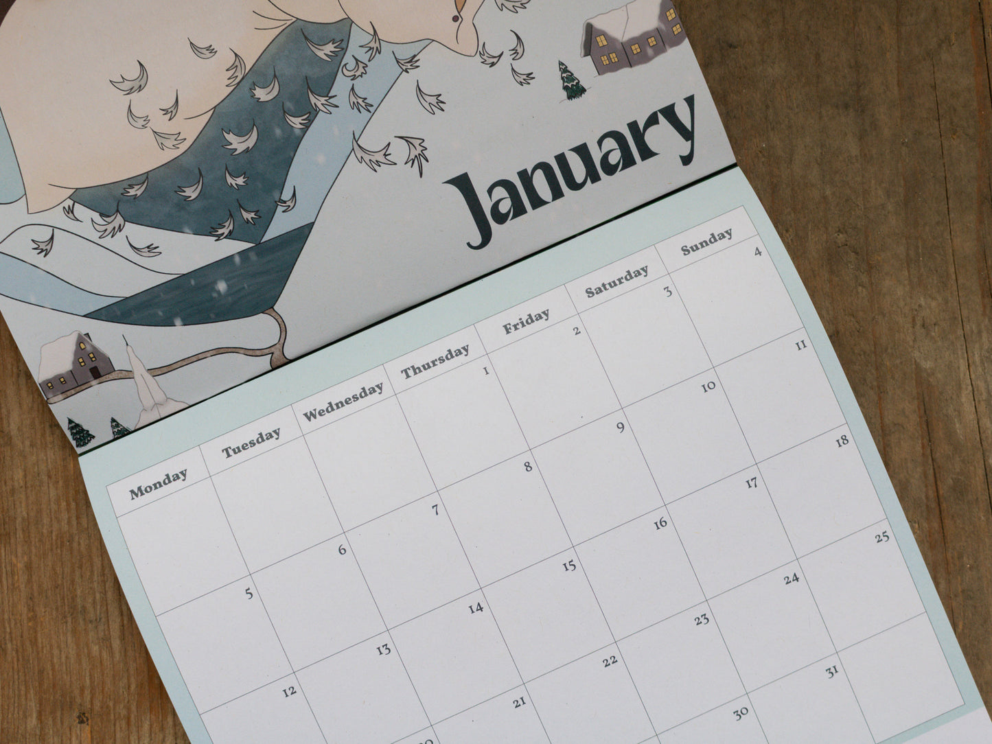 Calendar page for January with illustrations and ate grid on a wooden surface
