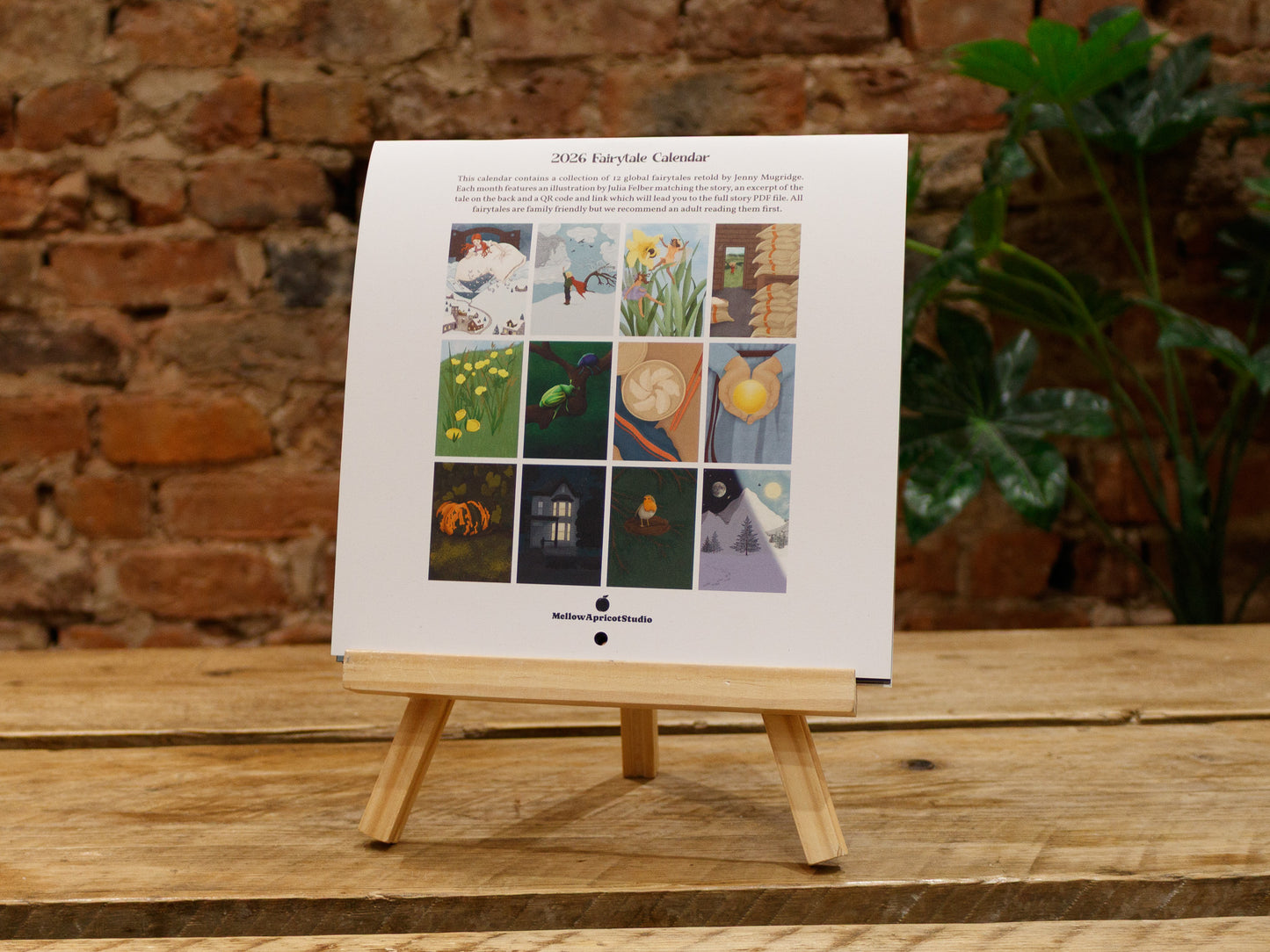 2026 Fairytale Calendar - backside - with a wooden stand against a brick wall background