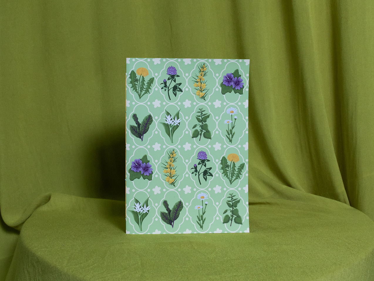 Sketchbook with floral pattern on a green fabric background