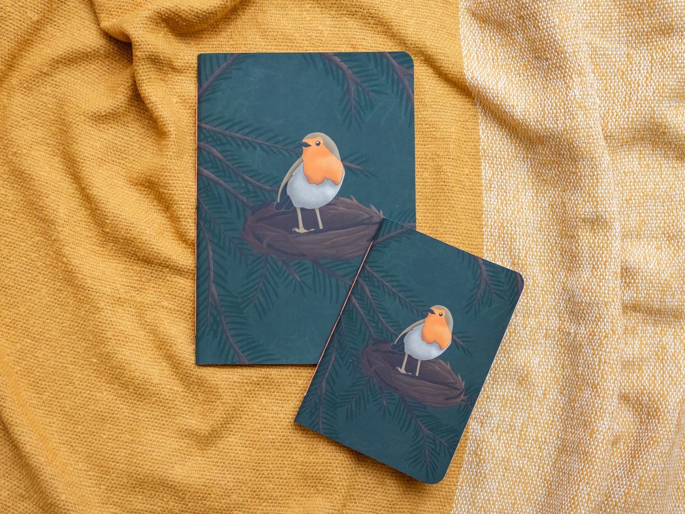 Two notebook covers with a robin design on a textured yellow fabric background