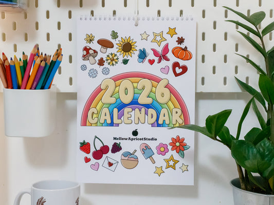 2026 calendar with colourful design on a pegboard with stationery items.