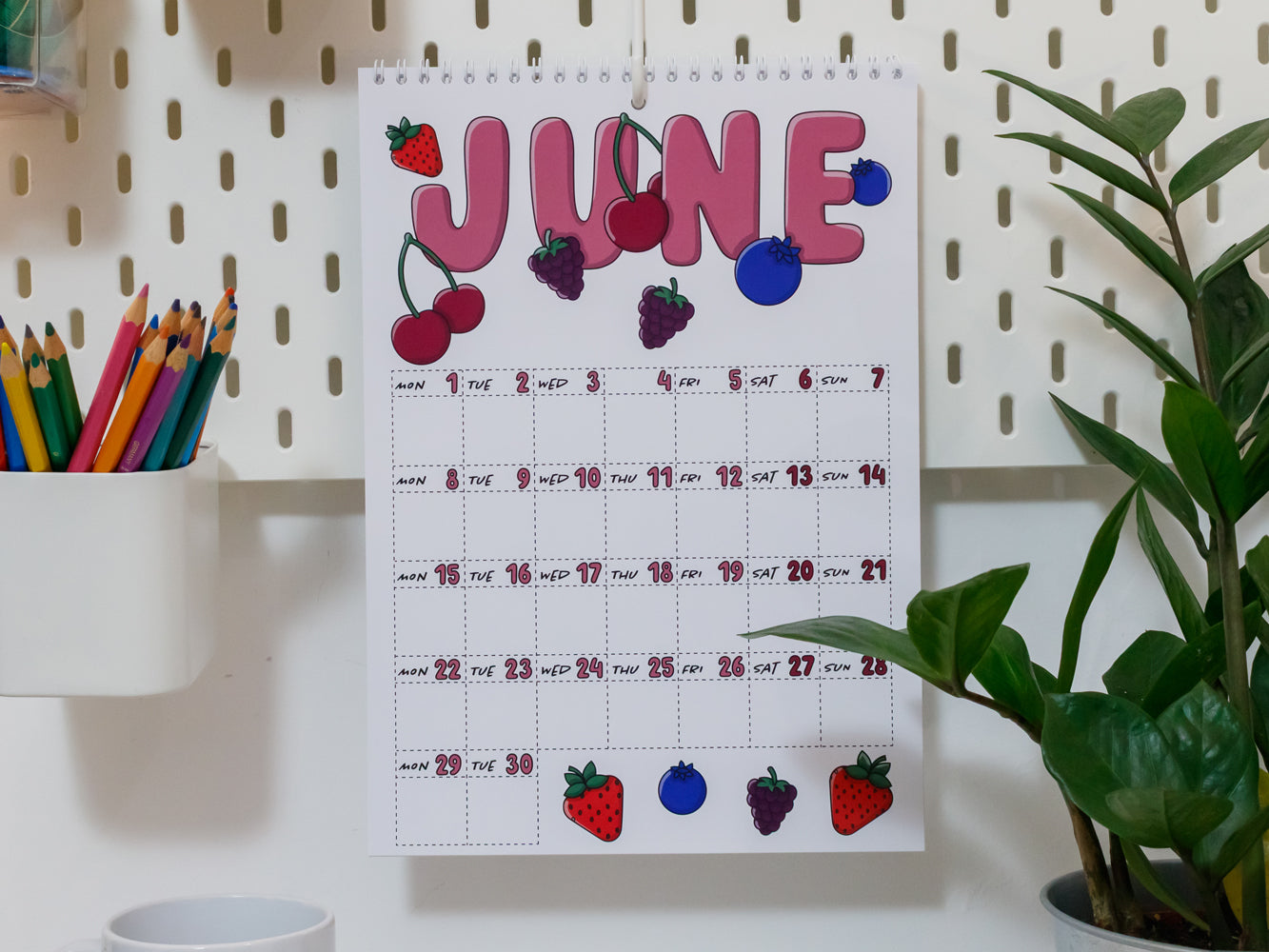 2026 Wall Calendar: June page with colourful fruit decorations on a pegboard wall.