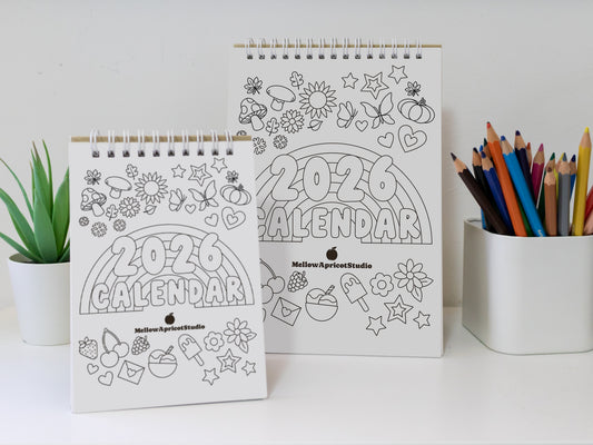 Two 2026 colouring desk calendar design on a white surface with coloured pencils.