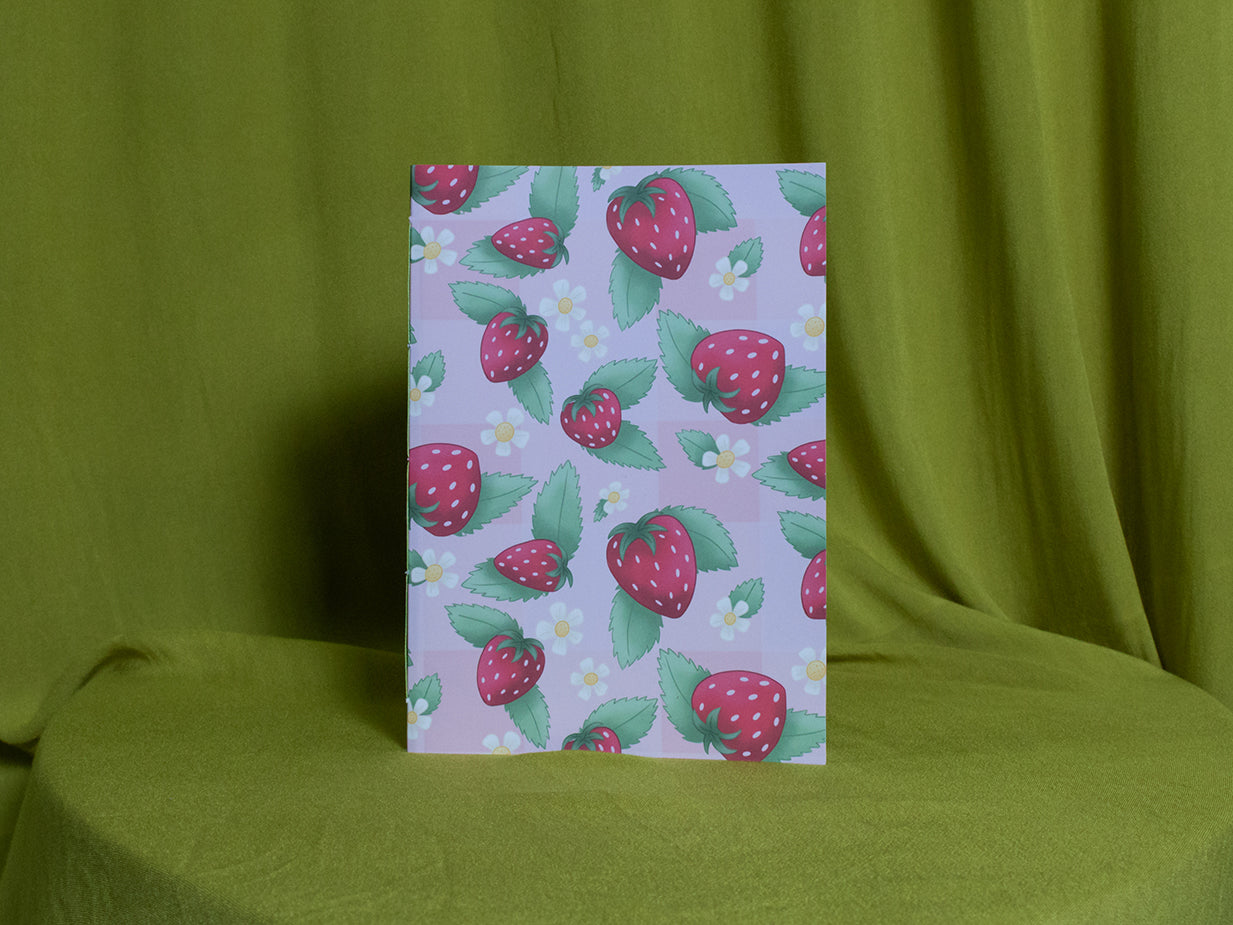 Sketchbook with strawberry pattern on a green fabric background