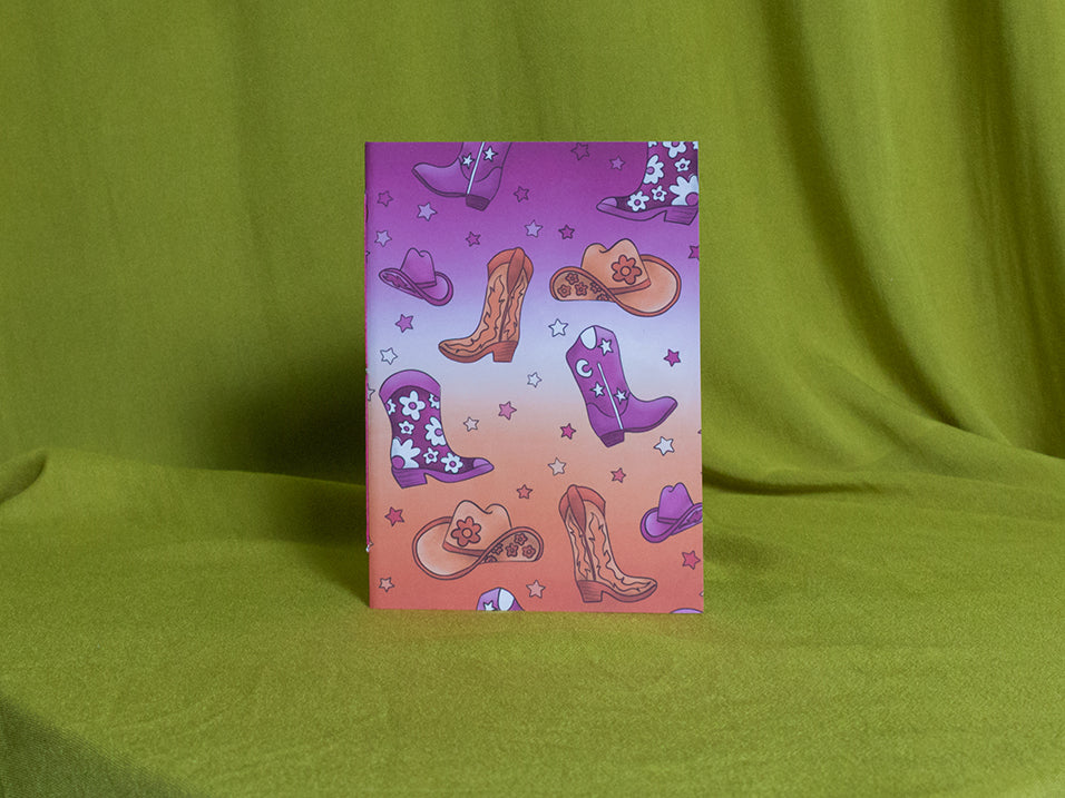 Small sketchbook with cowboy boot and hat design on a green fabric background