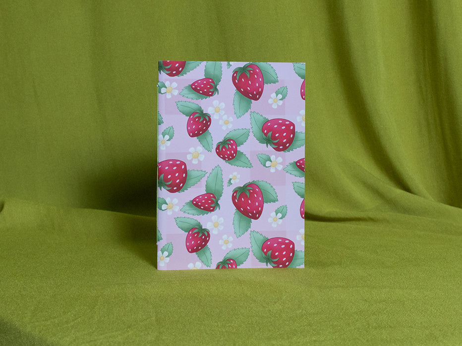 Small sketchbook with strawberry pattern on a green fabric background