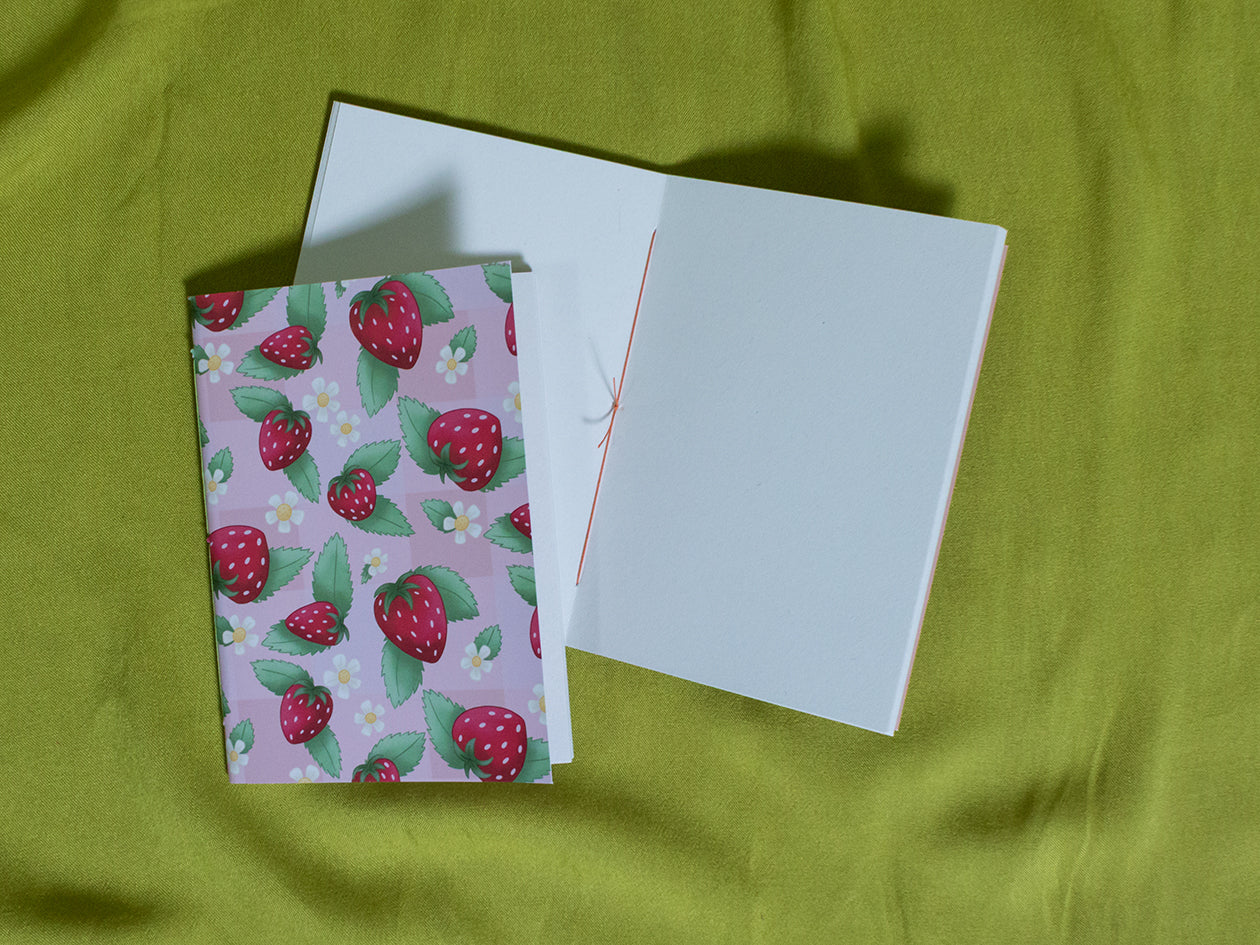 Small sketchbook with strawberry pattern on a green fabric background
