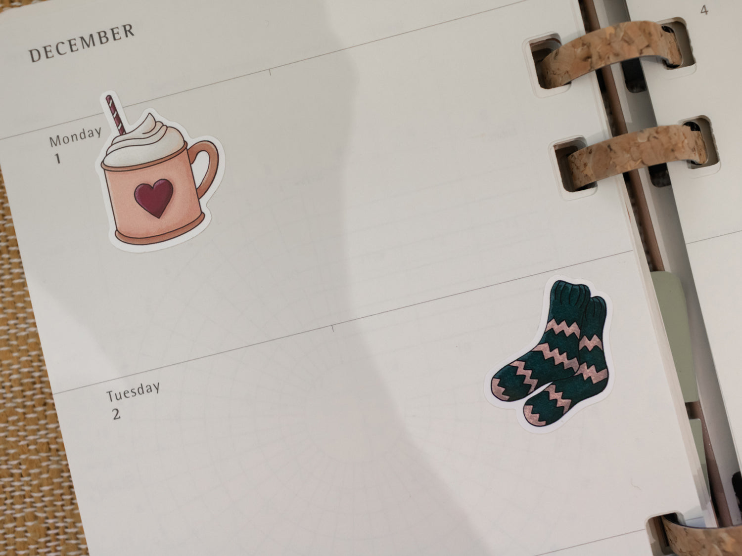 Calendar page with a hot cacao cup sticker and a pair of socks on a white background