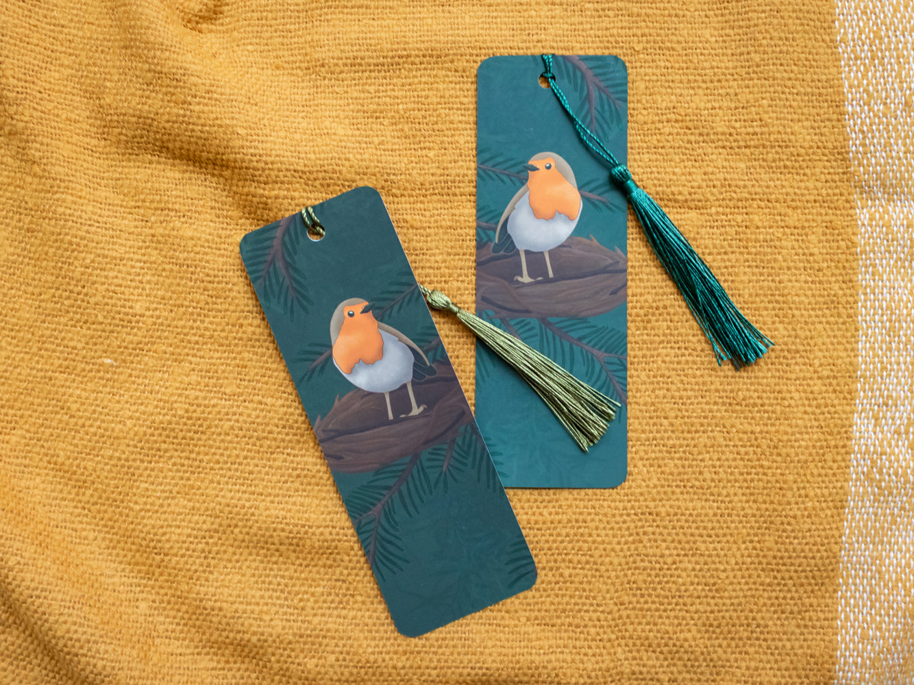 Two bookmarks with robin illustrations on a yellow textured fabric background