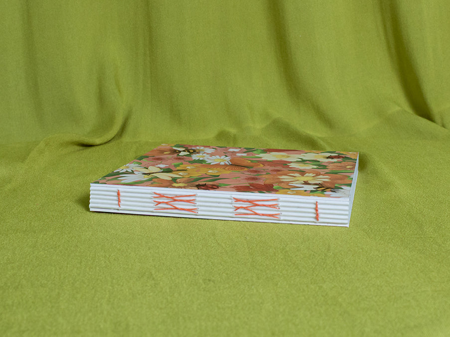 Open spine sketchbook with floral design on a green fabric background