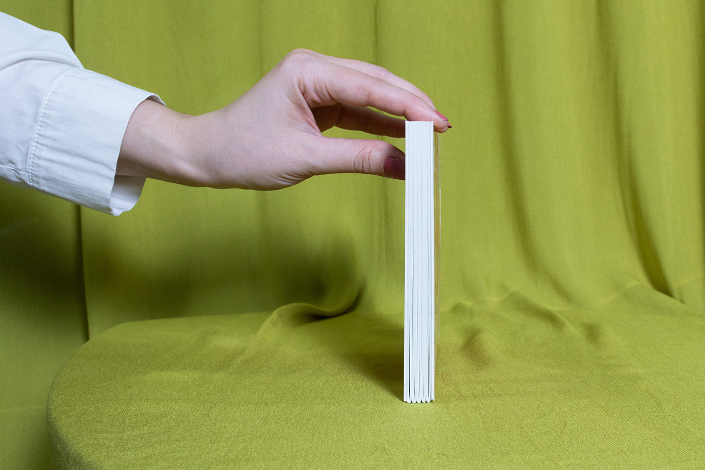 Hand holding a sketchbook against a green curtain background