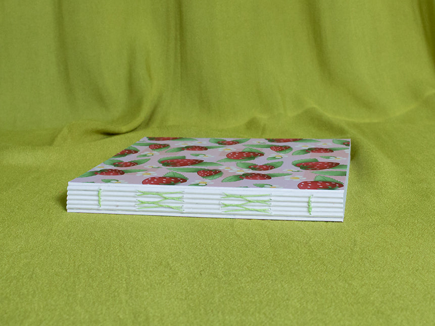 Square sketchbook with strawberry pattern on a green fabric background