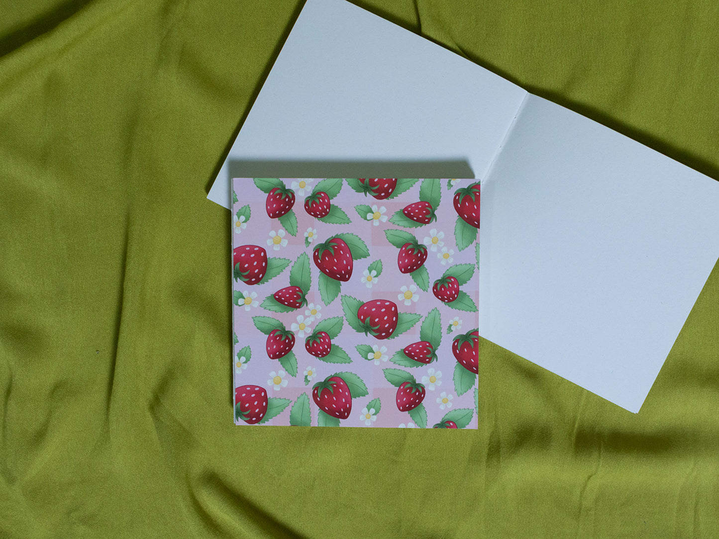 Square sketchbook with strawberry pattern on a green fabric background